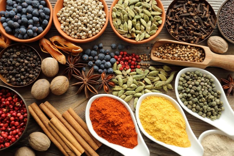 a variety of spices in spoons and on a table