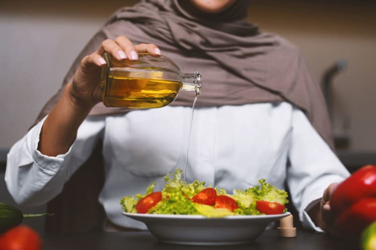 Muslim lady drizzling oil on her salad