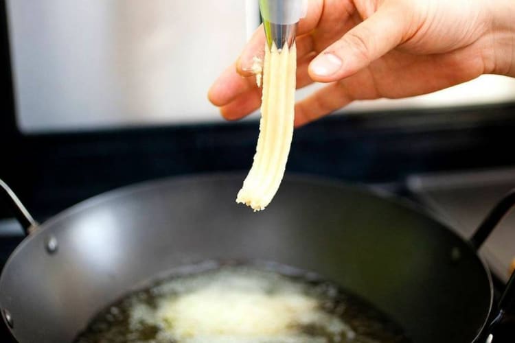 Fritter being dropped into hot oil