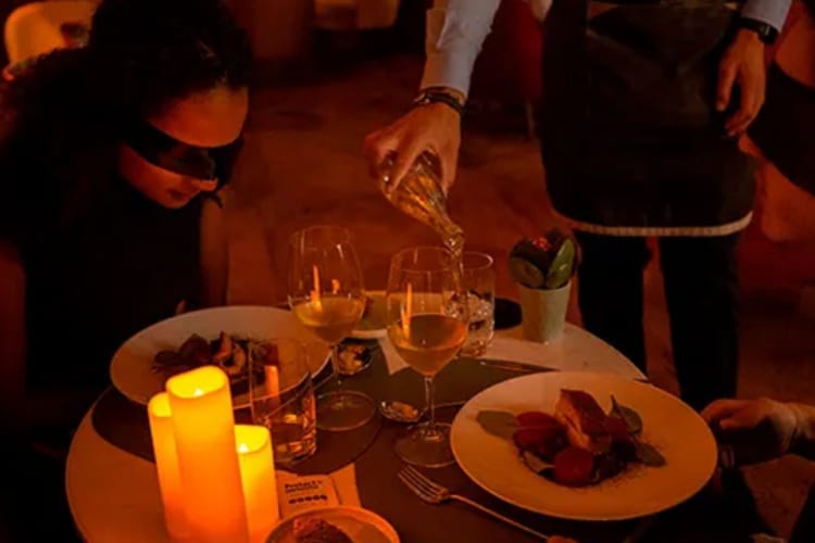 blindfolded diners smelling meal while server pours water