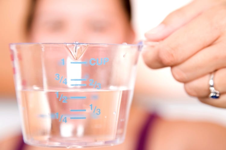 a measuring cup held by a woman in the background