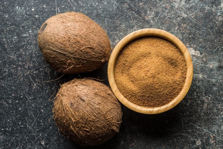 coconut sugar next to sliced coconuts