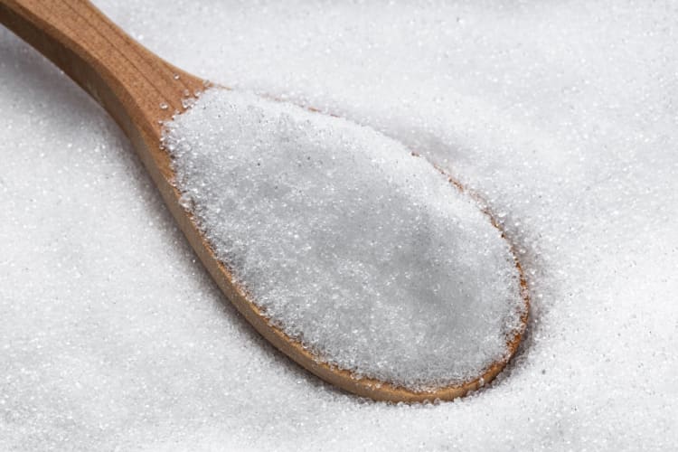 white erythritol powder in a wooden spoon