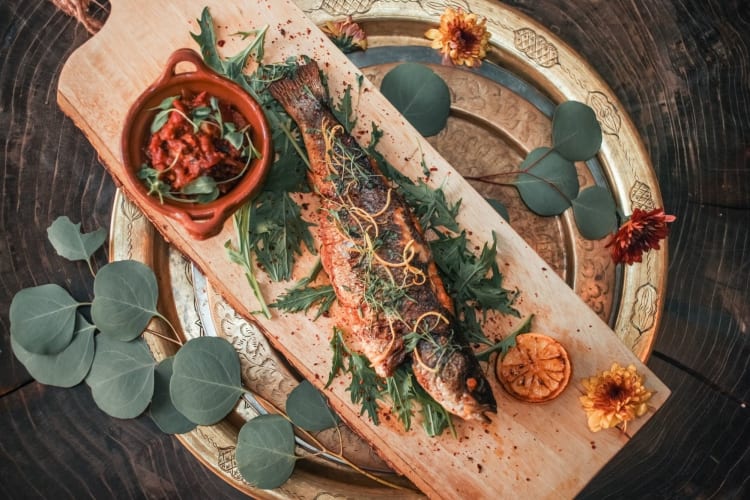 whole fish on wooden board with decorative with sides and spices