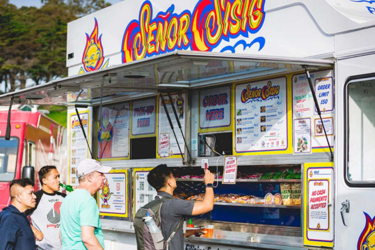 people lined up for a Filipino food truck on a sunny day