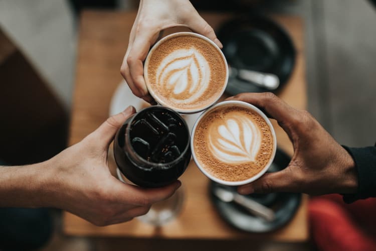 three hands clinking coffee cups