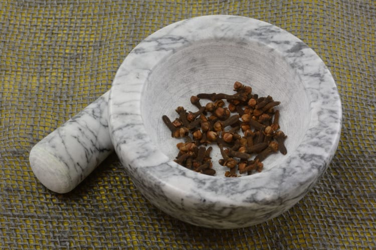 whole cloves with mortar and pestle