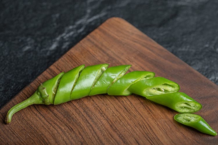 a neatly sliced serrano pepper on a cutting board