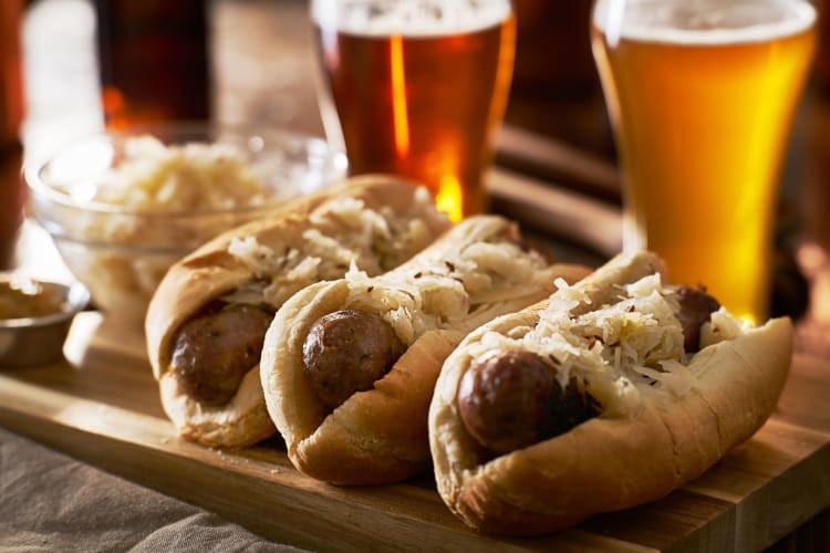 bratwurst sausage in buns beside glasses of beer