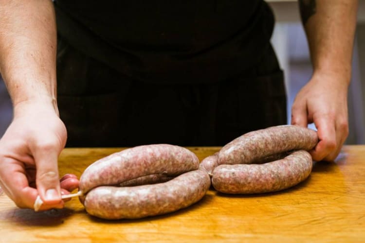 a chef tying the casings on homemade bratwurst