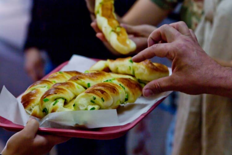 Food tour participants reach for Chinese scallion buns on a food tour.