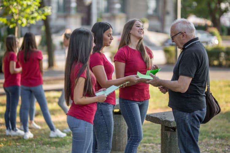 a group of students handing out green flyers to an older man