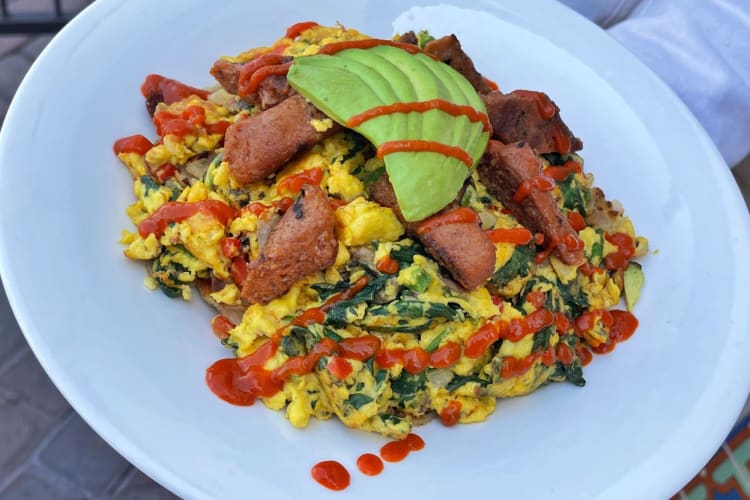 a waiter holding a spicy vegan bowl