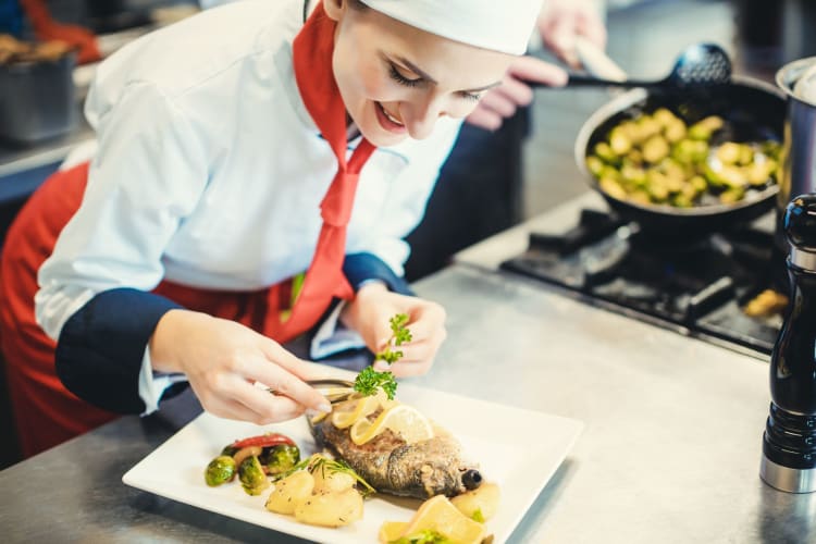 a female chef garnishing a fish dish