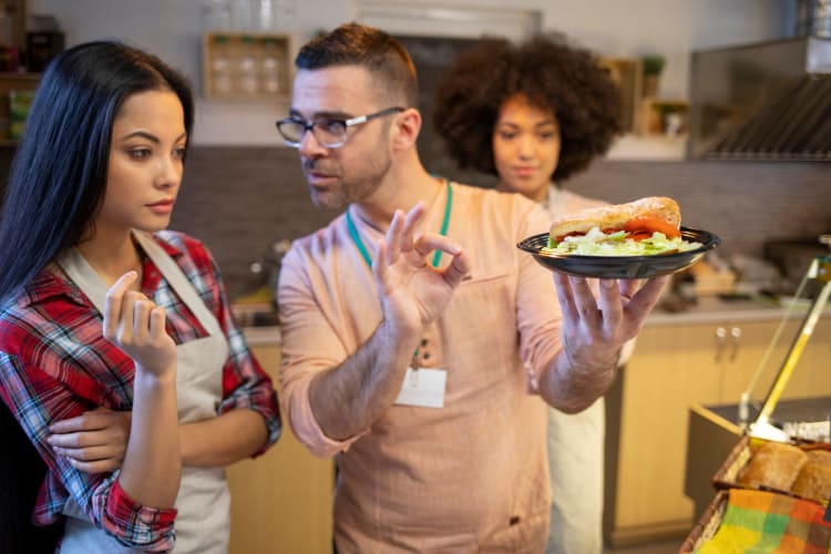 a chef gesturing while teaching cooking school students