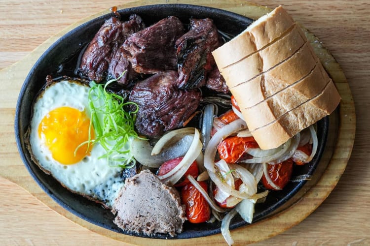 a plate of beef, vegetables, bread and an egg