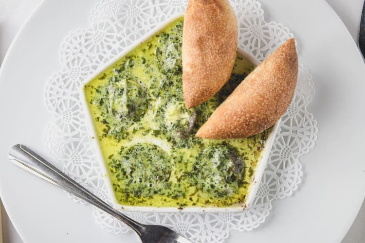 spinach-based soup with bread in a white dish