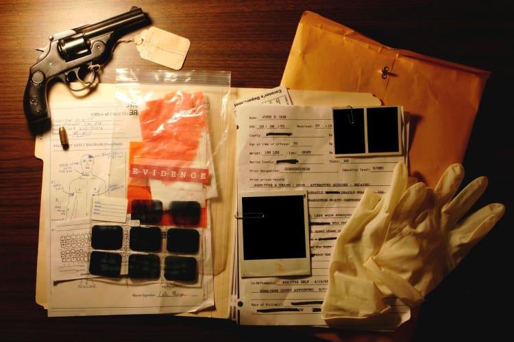 a variety of crime evidence examples on a board, including gloves and gun