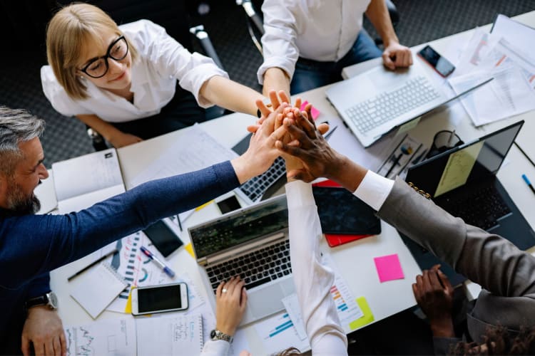 A group of co-workers giving each other a high-five at a table