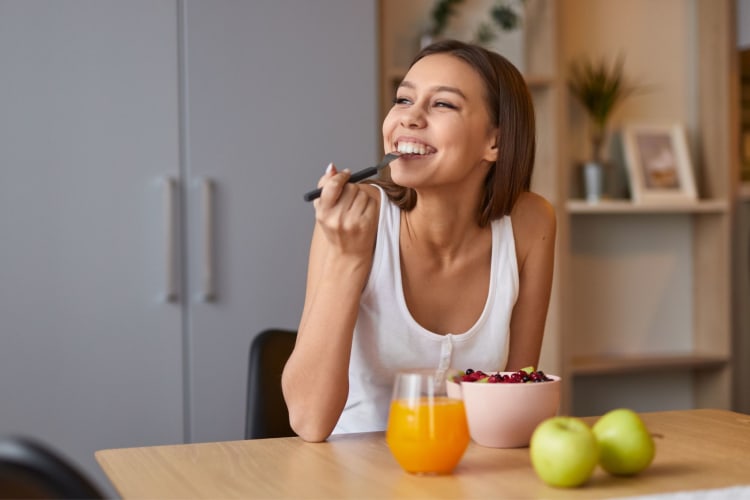 woman eating a bowl of fruit and smiling happily