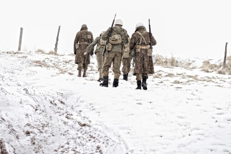 retro-style image of soldiers walking up a snowy hill in WWII