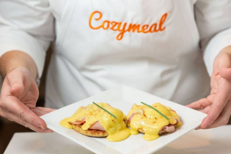 a chef presenting a plate of eggs Benedict