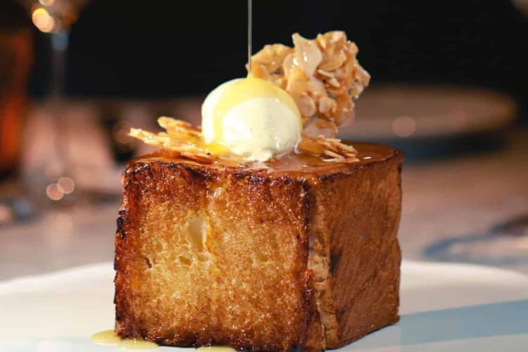 a cube of French toast being drizzled with syrup