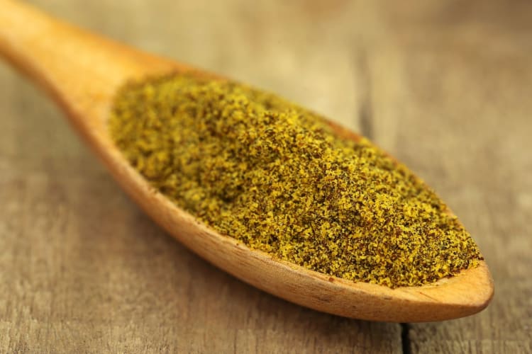 ground mustard on wooden spoon