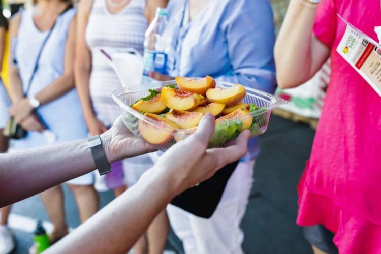 offering sliced peaches during a food tour