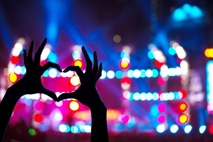 holding up fingers shaped like a heart at a concert