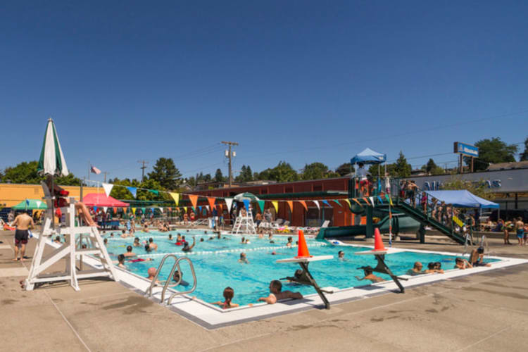 a busy public swimming pool with lifeguard stand