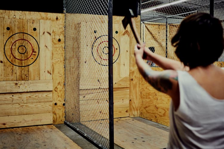 a woman about to throw an axe at a wooden throwing wall