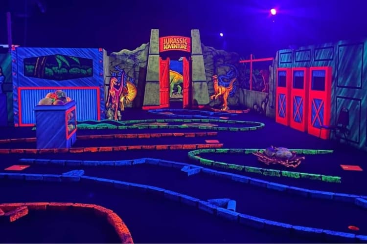 a neon-lit dinosaur-themed mini golf course