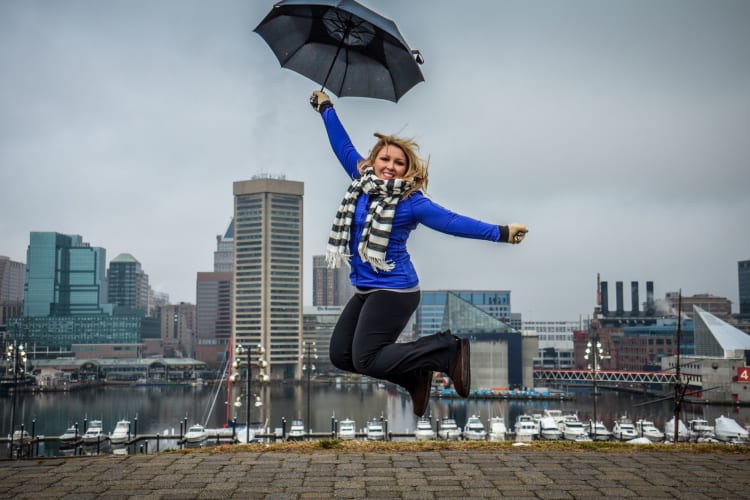 woman jumping with umbrella on cloudy day in Baltimore