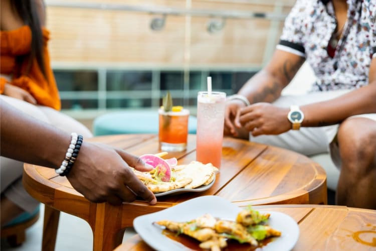 two men enjoying elevated bar bites and cocktails outside