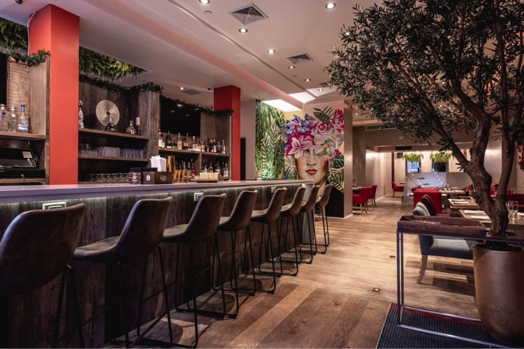 the colorful interior of an NYC restaurant, with a painting of a face as centerpiece