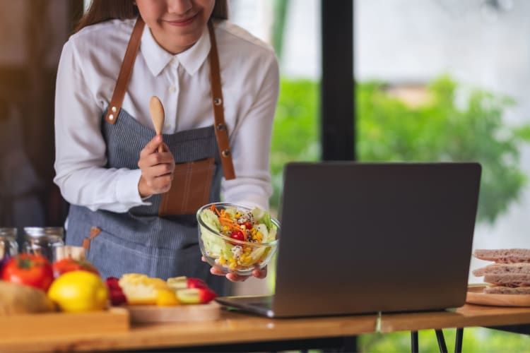 woman taking an online cooking class displaying a small salad