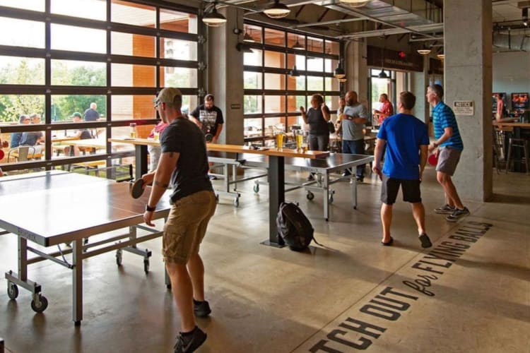 people playing ping pong in a well-lit games venue