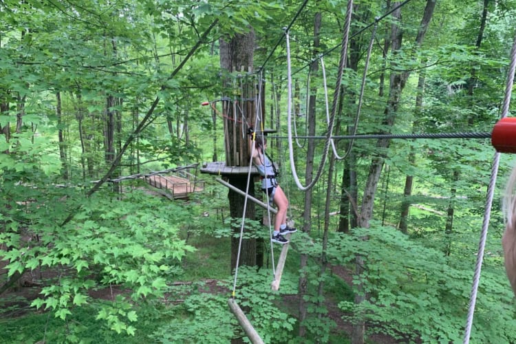 woman on a ropes course high in the trees