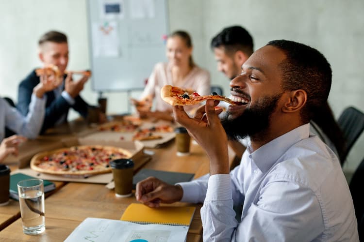 employees gathered around a table enjoying pizza