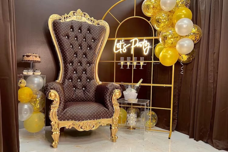 a fun selfie setup with a throne and a neon Let's Party sign