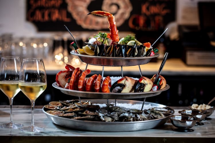 a seafood tower with three tiers next to white wine in glasses