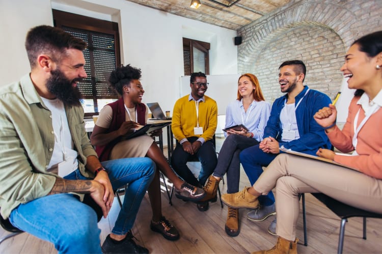 a group of co-workers sitting in a circle, laughing and talking