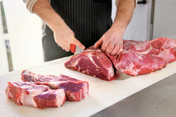 butcher cutting meat with a butcher knife