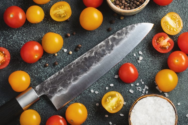 chef's knife on table with vegetables