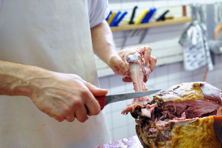 man deboning boiled ham