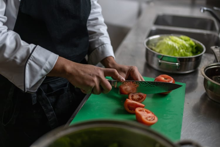 holding a chef's knife to cut tomatoes