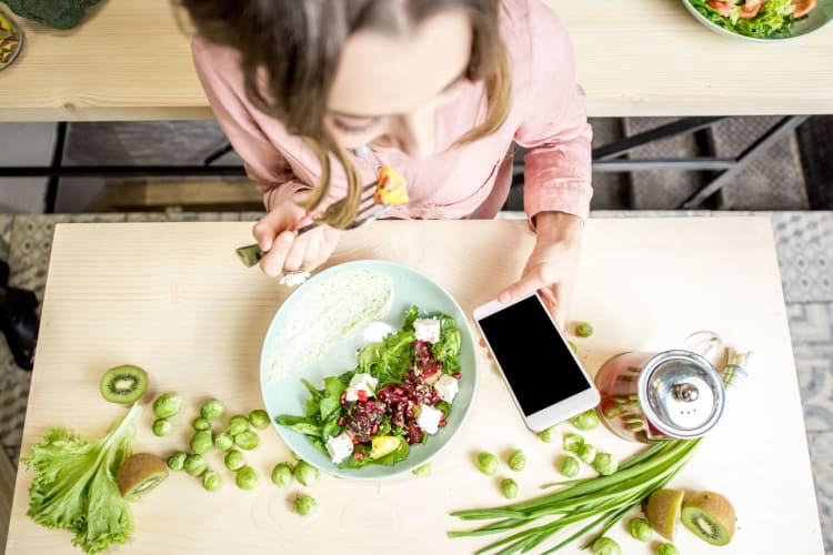 woman eating and looking at phone