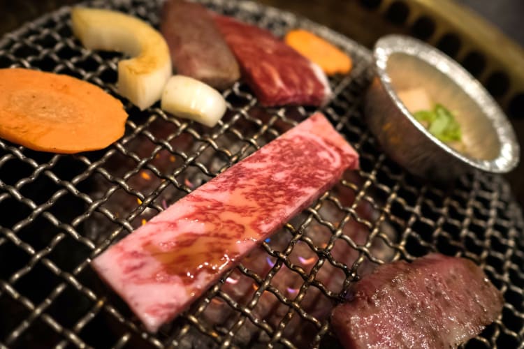 A5 wagyu cooking on a grill with sides