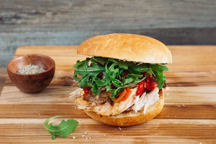 Chicken sandwich next to a small bowl of spices from Roli Roti food truck in San Francisco